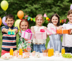 Rezepte Kindergeburtstag: Kinder stehen mit Geschenken vor Tisch